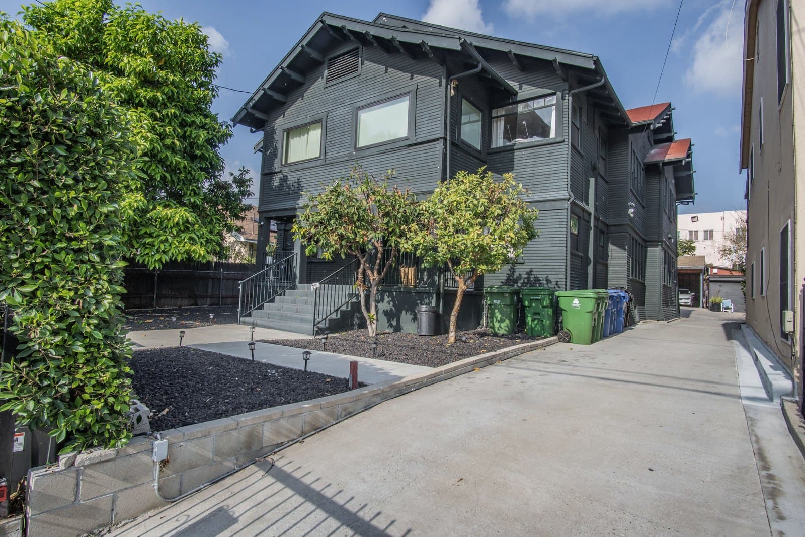 Side elevation showing the dark-clad Craftsman massing and mature landscaping